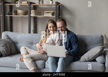 Glückliche Familie schwanger Paar entspannen sich auf bequeme Couch zusammen Stockfoto