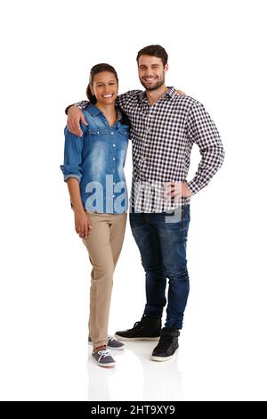 Glücklich und verliebt. Studioportrait eines liebevollen jungen Paares, das mit den Armen um sich herum isoliert auf Weiß steht. Stockfoto