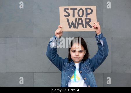 Kleines Mädchen isoliert auf einer Wand zeigt handgemachte Zeichen mit Stop war Nachricht. Stockfoto