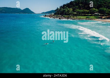 Surfer auf Surfbrett im transparenten blauen Ozean. Luftaufnahme Stockfoto