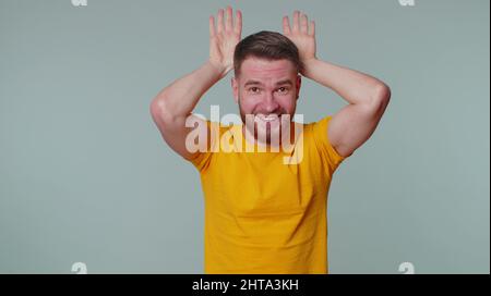 Ich bin kleiner Hase. Schöner, lustiger Mann, 20 Jahre alt, im T-Shirt, freundlich lächelnd und mit Hasenohren auf dem Kopf, lustig, mit Summen dumm Stockfoto