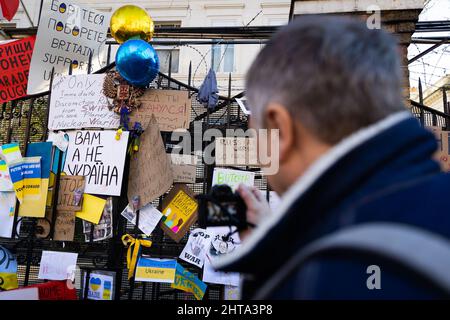 London, Großbritannien. 27.. Februar 2022. Ein Mann fotografiert die Plakate, die das Tor der russischen Botschaft während der Demonstration gegen die Invasion von Russiaís in der Ukraine in London schmücken. Kredit: SOPA Images Limited/Alamy Live Nachrichten Stockfoto