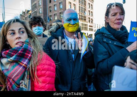 Während der massiven Demonstration gegen Putins Invasion der Ukraine, die am 27.. Februar 2022 in Amsterdam organisiert wurde, hat ein Mann sein Gesicht mit den Farben der ukrainischen Flagge bemalt. Nach Putins Entscheidung, die Ukraine anzugreifen, wurden am selben Tag mehrere Proteste im Zentrum der Stadt organisiert, um ihre Unterstützung für das ukrainische Volk zu zeigen. Die ukrainische Gemeinschaft, die russische Gemeinschaft und mehrere Nichtregierungsorganisationen in den Niederlanden, begleitet von Tausenden von Menschen, versammelten sich auf dem Dam-Platz, um gegen Putin und den Krieg in der Ukraine zu protestieren (Foto: Romy Fernandez/Sipa Stockfoto