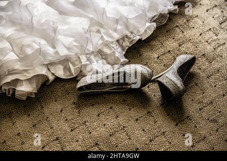 Nahaufnahme der Schuhe und des Hochzeitskleides auf dem Boden Stockfoto