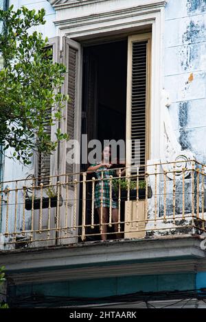 Die junge Frau praktiziert die Geige in einer gewölbten Tür von der Vorderseite ihres Hauses in Havanna, Kuba. Stockfoto