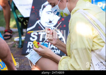 Bangkok, Thailand. 27.. Februar 2022. Ukrainische Demonstranten malen die Maske eines Freundes mit einer ukrainischen Flagge. Vor dem protestmarsch zum Benjakitti Park. (Foto: Adirach Toumlamoon/Pacific Press/Sipa USA) Quelle: SIPA USA/Alamy Live News Stockfoto