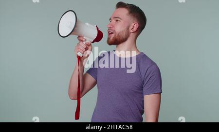 Lächelnder bärtiger Mann, der mit dem Megaphon spricht, Nachrichten verkündet und laut Verkaufswerbung ankündigt Stockfoto