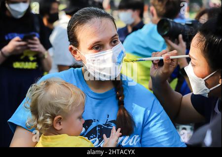 Bangkok, Thailand. 27.. Februar 2022. Ukrainische Demonstranten malen die Maske eines Freundes mit einer ukrainischen Flagge. Vor dem protestmarsch zum Benjakitti Park. (Foto: Adirach Toumlamoon/Pacific Press/Sipa USA) Quelle: SIPA USA/Alamy Live News Stockfoto