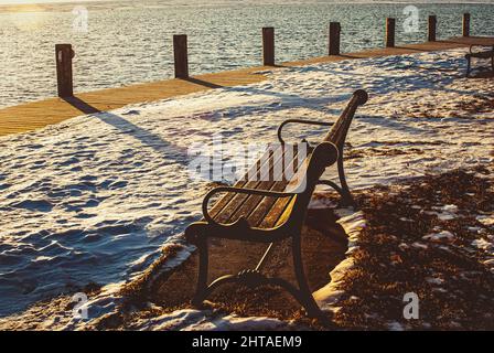 Wintermorgen auf dem Fluss mit Parkbänken am Wasser entlang Stockfoto