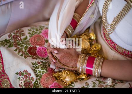 Nahaufnahme der Hände einer Braut, die mit Henna und wunderschönem Schmuck bei einer indischen Hochzeit bedeckt ist Stockfoto