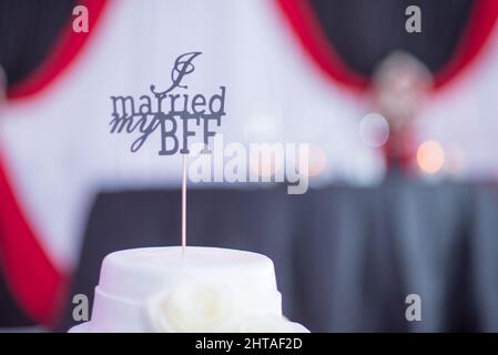 Selektive Fokusaufnahme einer weißen Hochzeitstorte mit einem Schild, auf dem steht: „Ich habe meinen BFF geheiratet“ Stockfoto