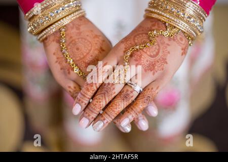 Selektive Nahaufnahme der Hände einer Braut, die mit Henna und traditionellem indischen Hochzeitsschmuck bedeckt ist Stockfoto