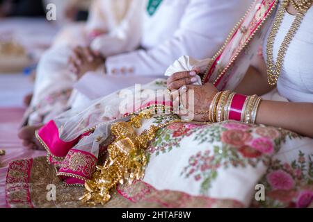 Nahaufnahme der Hände einer indischen Braut, die mit wunderschönem Henna und Goldschmuck bedeckt ist Stockfoto