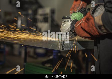 Nahaufnahme der Hände eines Mannes mit einem Schleifer mit Schneidescheibe. Stockfoto
