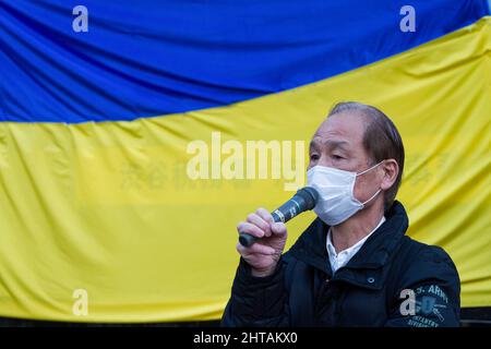 Tokio, Japan. 27.. Februar 2022. Ein Japaner spricht vor einer ukrainischen Flagge während eines Protestes gegen die russische Invasion der Ukraine auf dem Hachiko-Platz. Kredit: SOPA Images Limited/Alamy Live Nachrichten Stockfoto