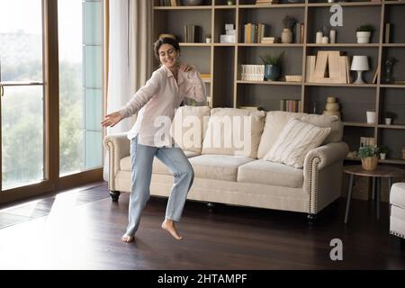 Glückliche, sorglose hispanische Frau, die zu Hause tanzt. Stockfoto