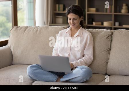 Glückliche 25s junge hispanische Frau mit Computer zu Hause. Stockfoto