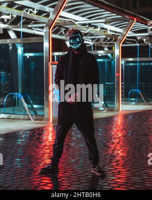 Mann in einer blauen Neonmaske stehend Stockfoto