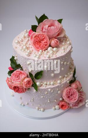 Vertikales Foto von zweilagiger Buttercremkuchen mit essbaren Perlen und Rosen Stockfoto