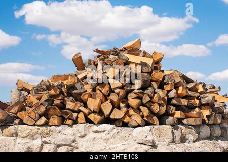 Ein Stapel von Baumstämmen für den Ofen, übereinander gegen den blauen Himmel gestapelt Stockfoto