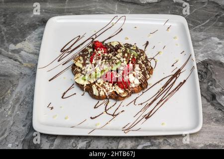 Nahaufnahme von belgischen Waffeln mit Erdbeeren, Heidelbeeren und Sirup Stockfoto