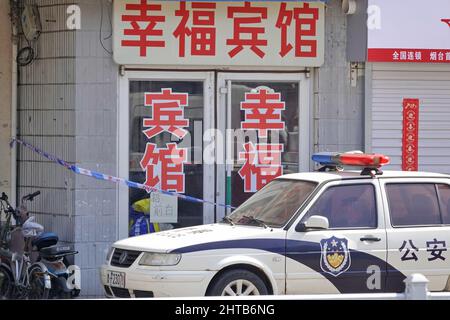 YANTAI, CHINA - 28. FEBRUAR 2022 - Polizeibeamte stehen Wache am Eingang des Happiness Hotels in Yantai, Provinz Shandong, wo bestätigt wurde Stockfoto