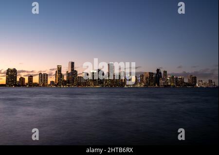 Stadtbild der Innenstadt von Miami, blaue Stunde mit Sonnenuntergang. Die Lichter der Stadt und der South Channel von Miami. Blick auf das luxuriöse und Business Center von Brickell. Stockfoto