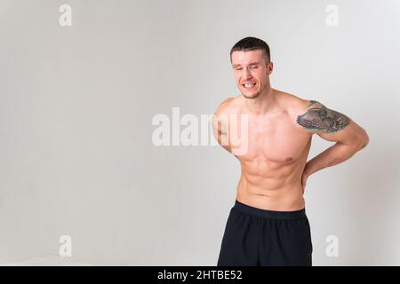 Ein Mann Rückenschmerzen hält seine Hand auf seinem Rücken Schmerzen Person isoliert jungen Erwachsenen, halten. Halskrankheit halten, Rücken attraktiv leiden Stockfoto