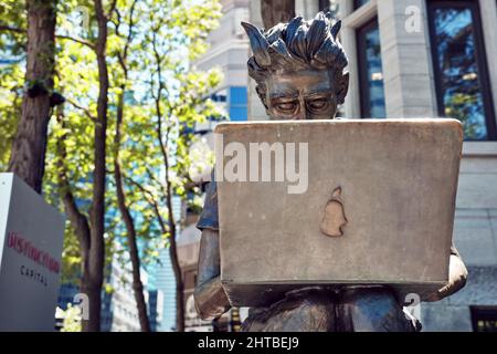 Juni, 2018 - Montreal, Kanada: Statue der McGill-Universität, die auf einer Bank sitzt und einen Laptop-pc in der Sherbrooke Street in Montreal, Quebec, verwendet Stockfoto