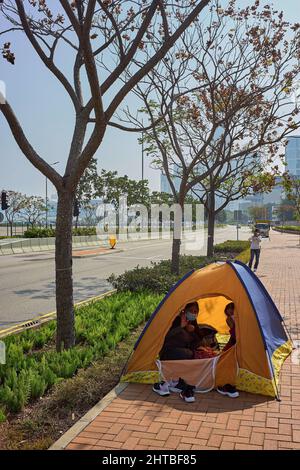 Hongkong, China. 27.. Februar 2022. Zwei ausländische Haushelfer verbringen ihren Sonntagstag in einem Zelt im Bezirk Admiralty in Hongkong. Hongkong verschärft die Regeln der sozialen Distanzierung, um der schlimmsten Epidemie entgegenzuwirken, indem es unter allen Umständen Masken im Freien trägt und sich auf zwei Personen beschränkt. Kredit: SOPA Images Limited/Alamy Live Nachrichten Stockfoto