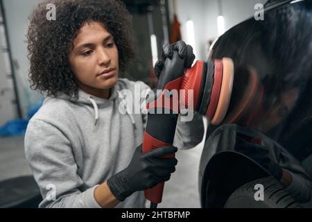 Qualifizierter Mitarbeiter der Tankstelle Polieren Automobil mit Puffer Stockfoto