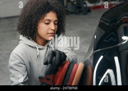 Ruhige, konzentrierte Arbeiterin, die Kraftfahrzeuge abpuffert Stockfoto