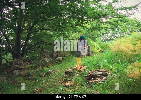 Camping Zelt Holz Lagerfeuer Mann Schärfstab Stockfoto