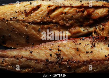 Nahaufnahme von zwei Filets geräucherter Makrele mit gemahlenem schwarzem Pfeffer Stockfoto