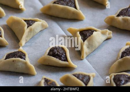 Vorgebackene 'Haman Pockets', auch bekannt als Hamantashen, ein aschkenasisch-jüdisches dreieckiges gefülltes Plätzchen, das normalerweise mit dem jüdischen Feiertag in Verbindung gebracht wird Stockfoto