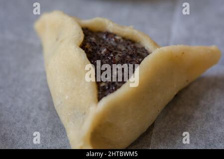 Nahaufnahme einer vorgebackenen 'Haman-Tasche', auch bekannt als Hamantashen, einem aschkenasischen jüdischen dreieckigen gefüllten Taschenkeks, der normalerweise mit dem Juden in Verbindung gebracht wird Stockfoto