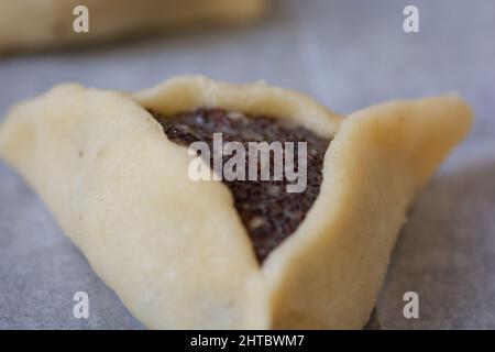 Nahaufnahme einer vorgebackenen 'Haman-Tasche', auch bekannt als Hamantashen, einem aschkenasischen jüdischen dreieckigen gefüllten Taschenkeks, der normalerweise mit dem Juden in Verbindung gebracht wird Stockfoto