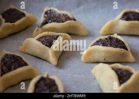 Vorgebackene 'Haman Pockets', auch bekannt als Hamantashen, ein aschkenasisch-jüdisches dreieckiges gefülltes Plätzchen, das normalerweise mit dem jüdischen Feiertag in Verbindung gebracht wird Stockfoto