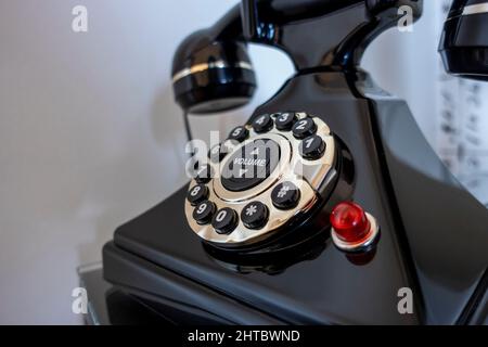 Abgewinkelte selektive Fokussierung auf ein schwarzes Drehtelefon auf einem Nachttisch im Schlafzimmer, aufgenommen vor weißem Hintergrund Stockfoto