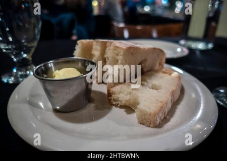 Nahaufnahme eines flauschigen, knusprig geschnittenen Brotes und cremiger Butter auf einem Teller als Vorspeise in einem High-End-Restaurant im pazifischen Nordwesten Stockfoto