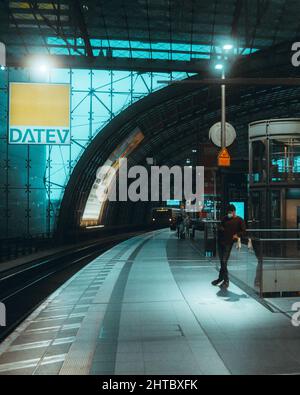 Vertikale Aufnahme des Mannes, der auf dem Bahnsteig der U-Bahn-Station auf den Zug wartet. Stockfoto