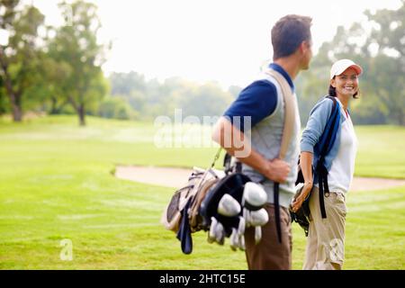 Golfspielerin lächelt und schaut auf den Mann. Konzentrieren Sie sich auf weibliche Golfspielerin lächeln und den Mann betrachten. Stockfoto