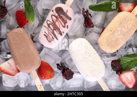 Nahaufnahme von hausgemachten Eiszapfen mit verschiedenen Geschmacksrichtungen über schwarzem Tisch mit Früchten Stockfoto