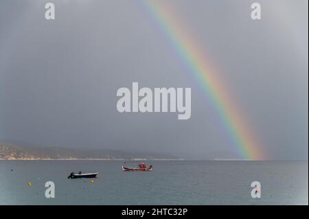 Regenbogen- und Fischerboote auf See. Das Foto wurde an einem bewölkten Tag aufgenommen Stockfoto