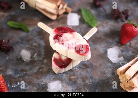 Nahaufnahme von hausgemachten Eiszapfen mit verschiedenen Geschmacksrichtungen über schwarzem Tisch mit Früchten Stockfoto