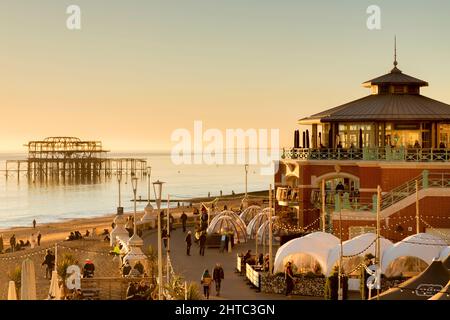 13. Januar 2022: Brighton, East Sussex, Großbritannien - Winter auf der Promenade von Brighton, mit Menschen, die am späten Nachmittag die Sonne genießen, und dem alten West Pier Stockfoto