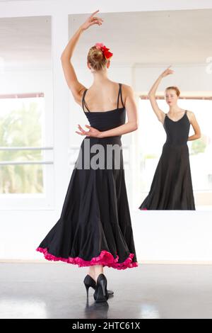 Sorgfältig kontrollierte Leidenschaft. Junge Tänzerin, die Flamenco in einem Tanzstudio aufführt. Stockfoto