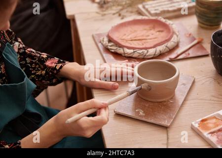 Gesichtslose Frau malt eine Tonschale Stockfoto