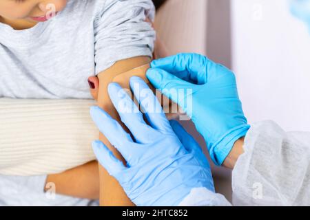 Nahaufnahme einer Ärztin, die nach der Injektion des Impfstoffes einen Gips auf das Kind aufgibt Stockfoto