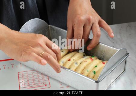 Weibliche Bakerin, die Roti Sisir, traditionelles indonesisches Pull-Apart-Brot, in der Regel mit Tee serviert. Arange Brot auf Backform Stockfoto